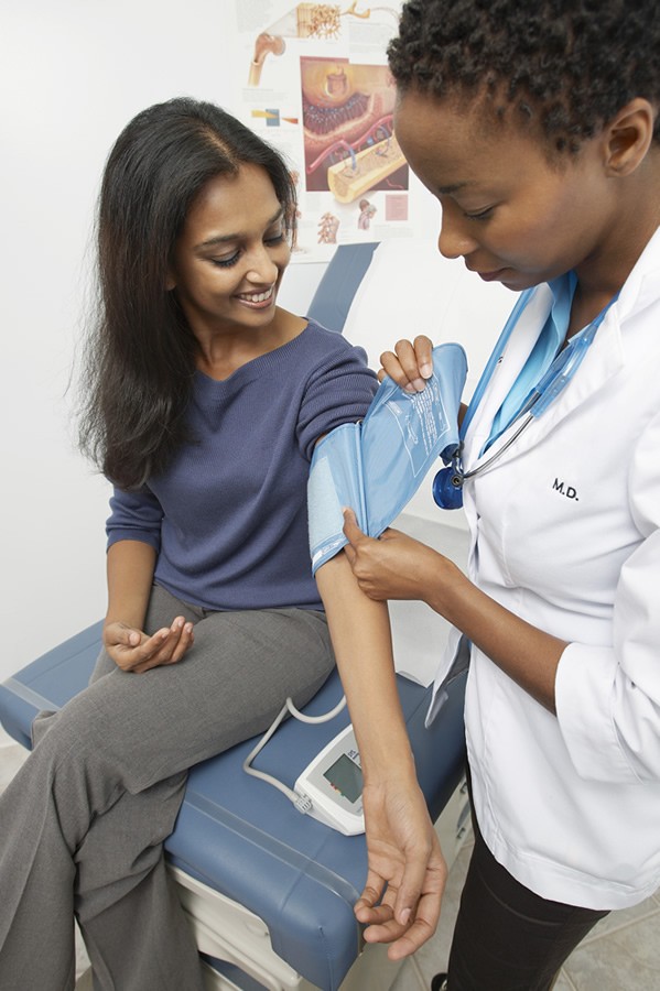 doctor checks womans blood pressure